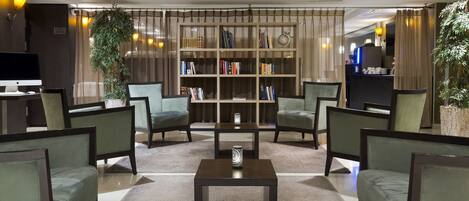 A modern lobby with a central coffee table, seating area, bookshelf, and a television.