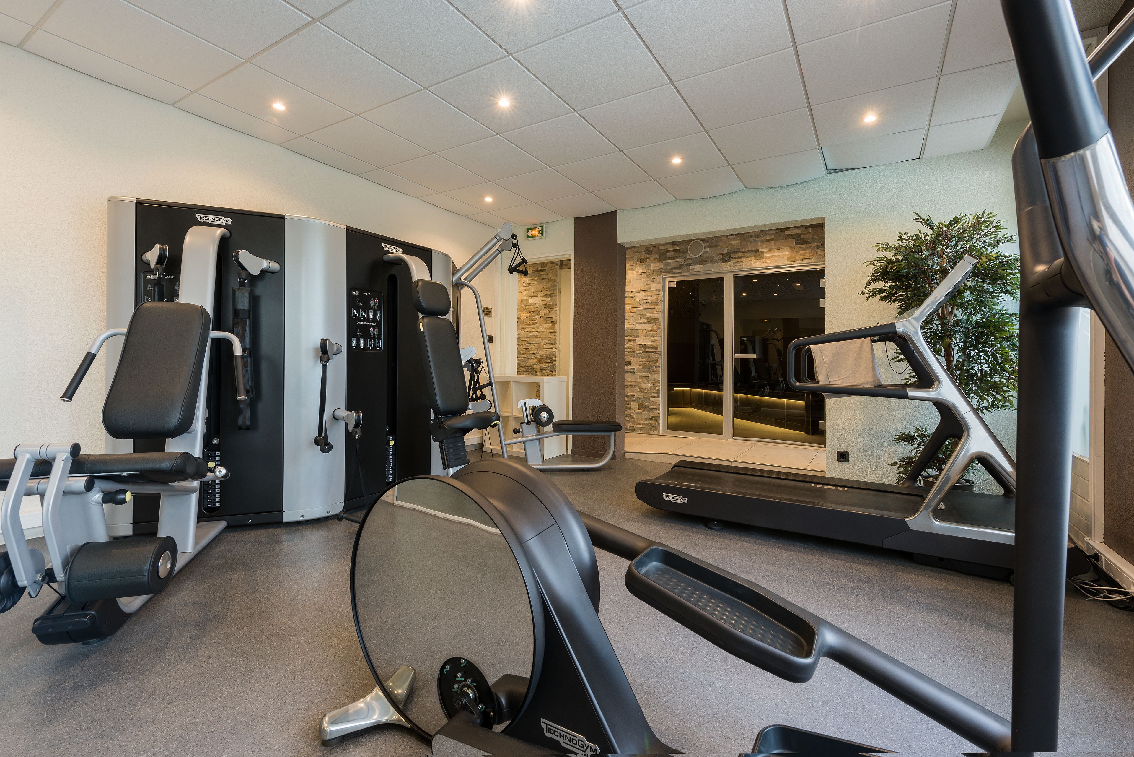 A gym with cardio machines, weight training equipment, and a walking path.