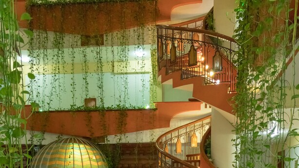 Een meerlaags atrium met een centrale trap, decoratieve lantaarns en hangende planten.