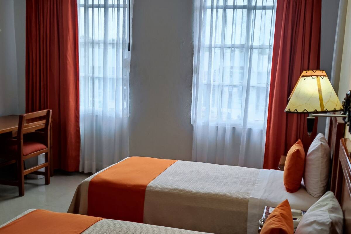 Une chambre d’hôtel avec deux lits, un bureau et une lampe.