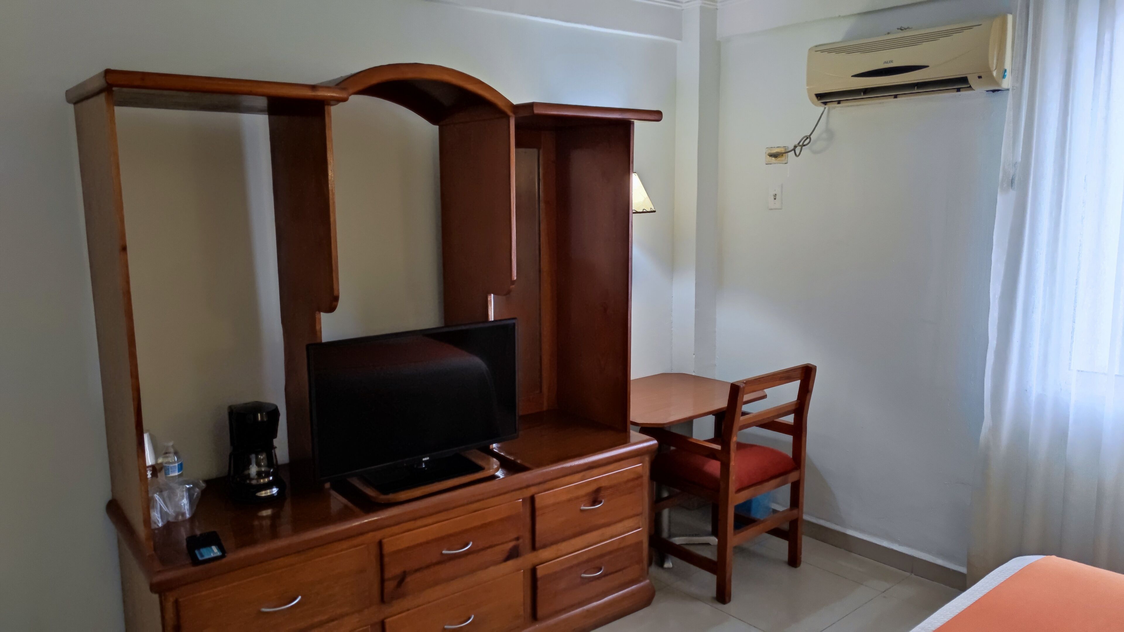 Een houten dressoir met een televisie, een stoel en een kleine tafel.