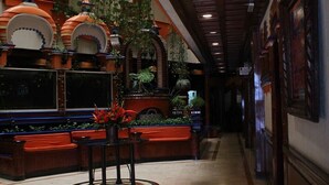 Een hotel lobby met een lange gang, rode zitplaatsen en decoratieve plantenbakken.