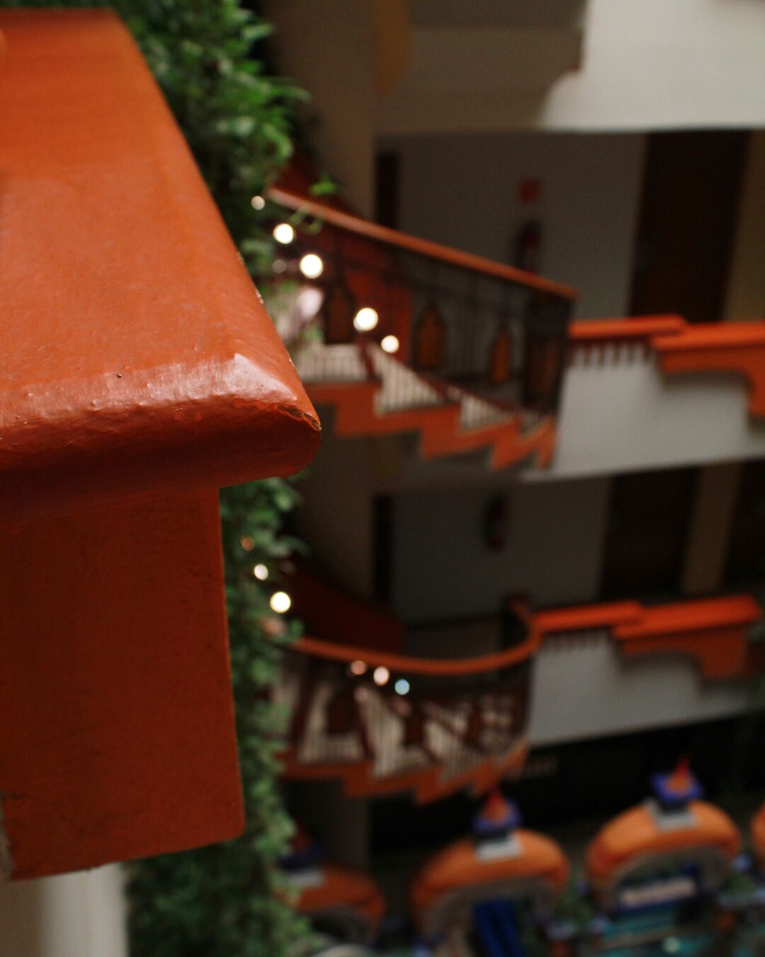 A multi-level building with orange railings and a green plant in the foreground.