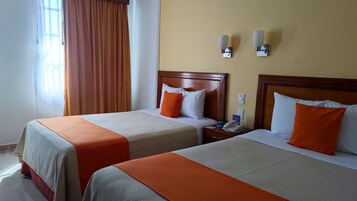 Dos camas dobles con ropa de cama naranja y blanca, cabeceros de madera, mesitas de noche con lámparas y una ventana con cortinas.