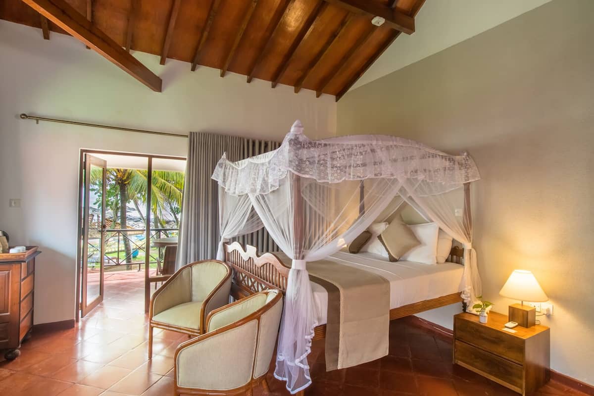 A bedroom with a canopy bed, a wooden nightstand, and a chair.