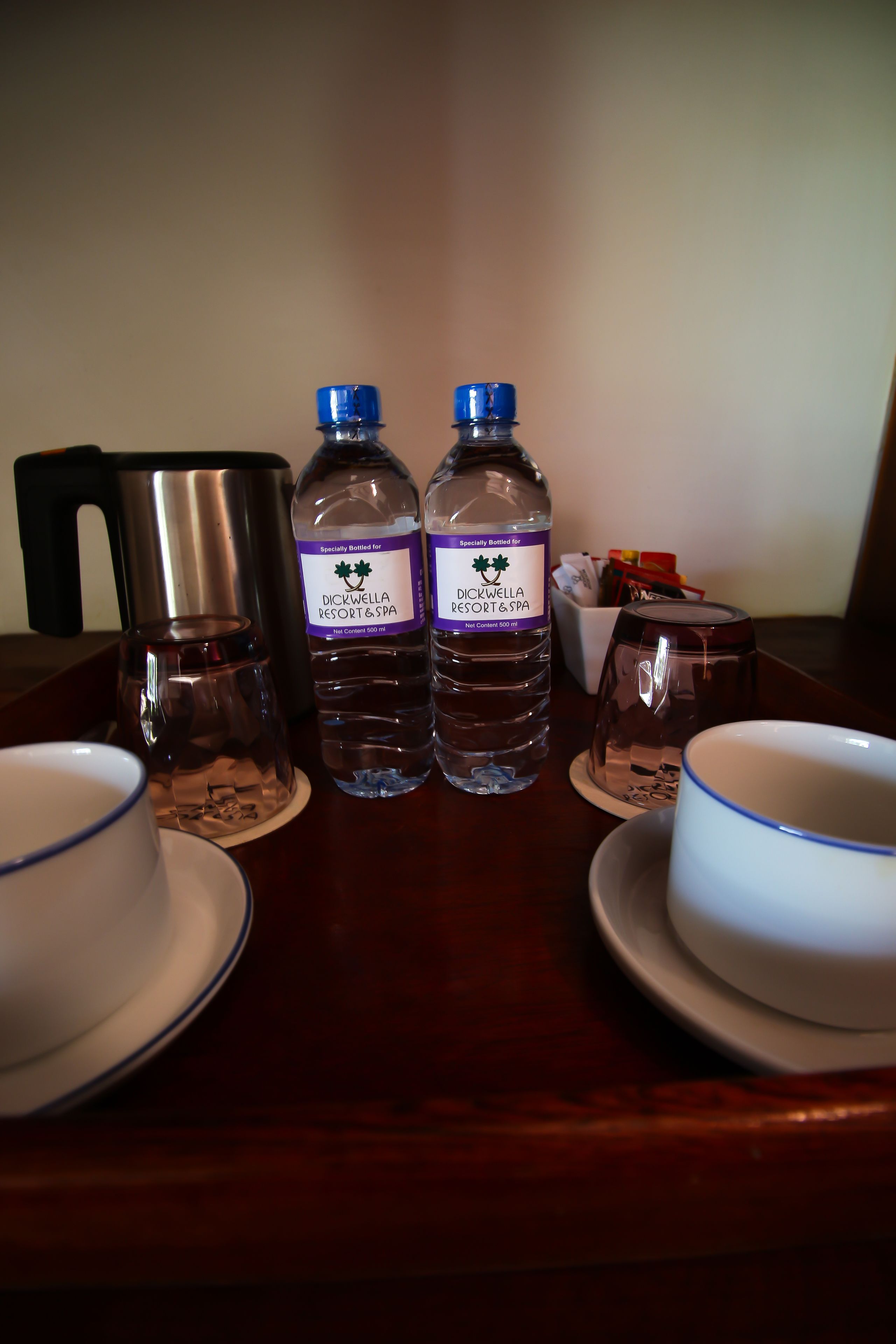 A table with a coffee pot, two water bottles, and two cups.