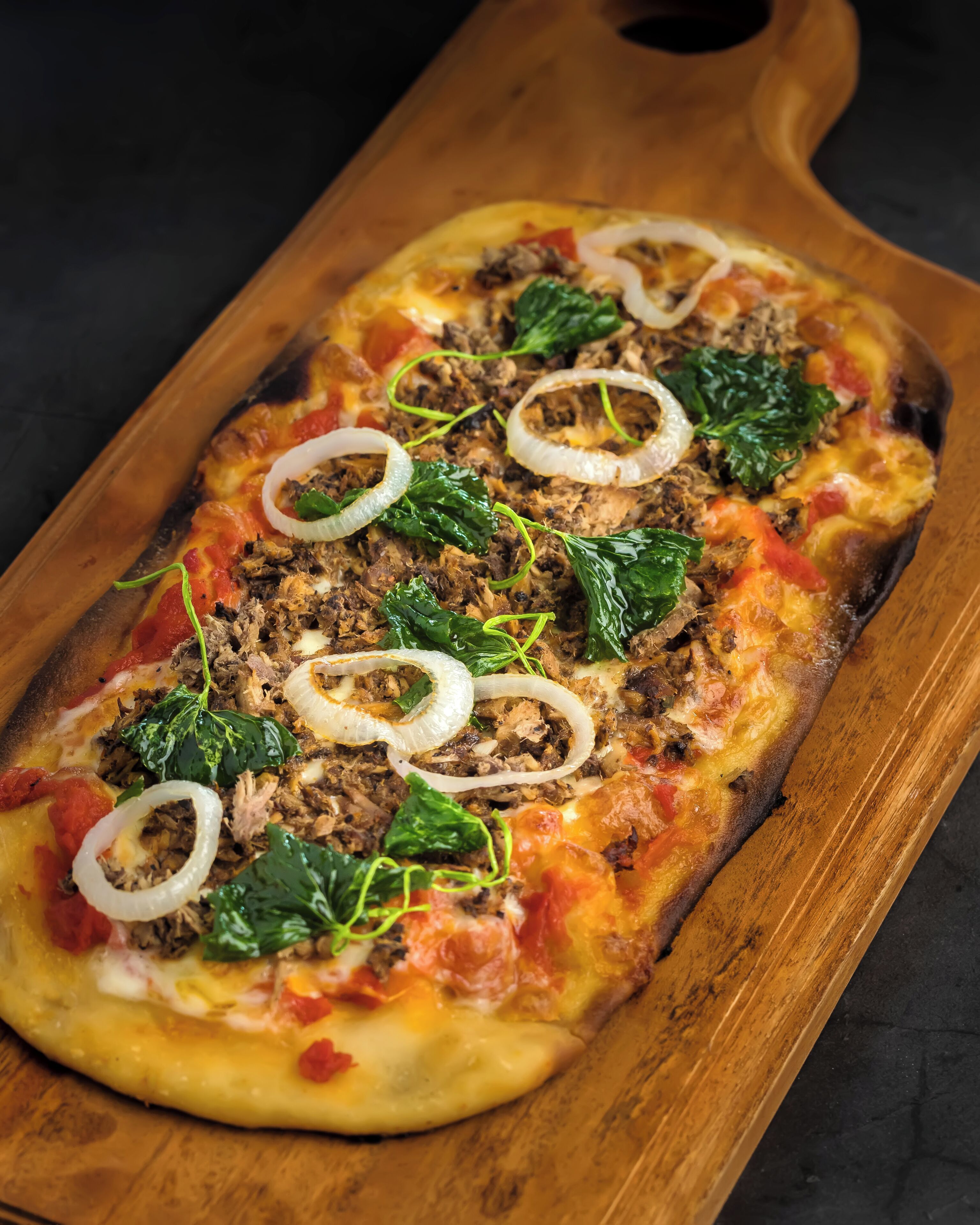 A pizza on a wooden board.