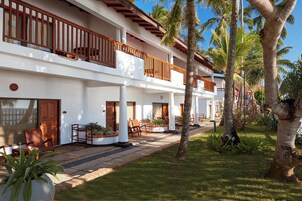 Um hotel com vários andares, varandas, área de estar ao ar livre e palmeiras.