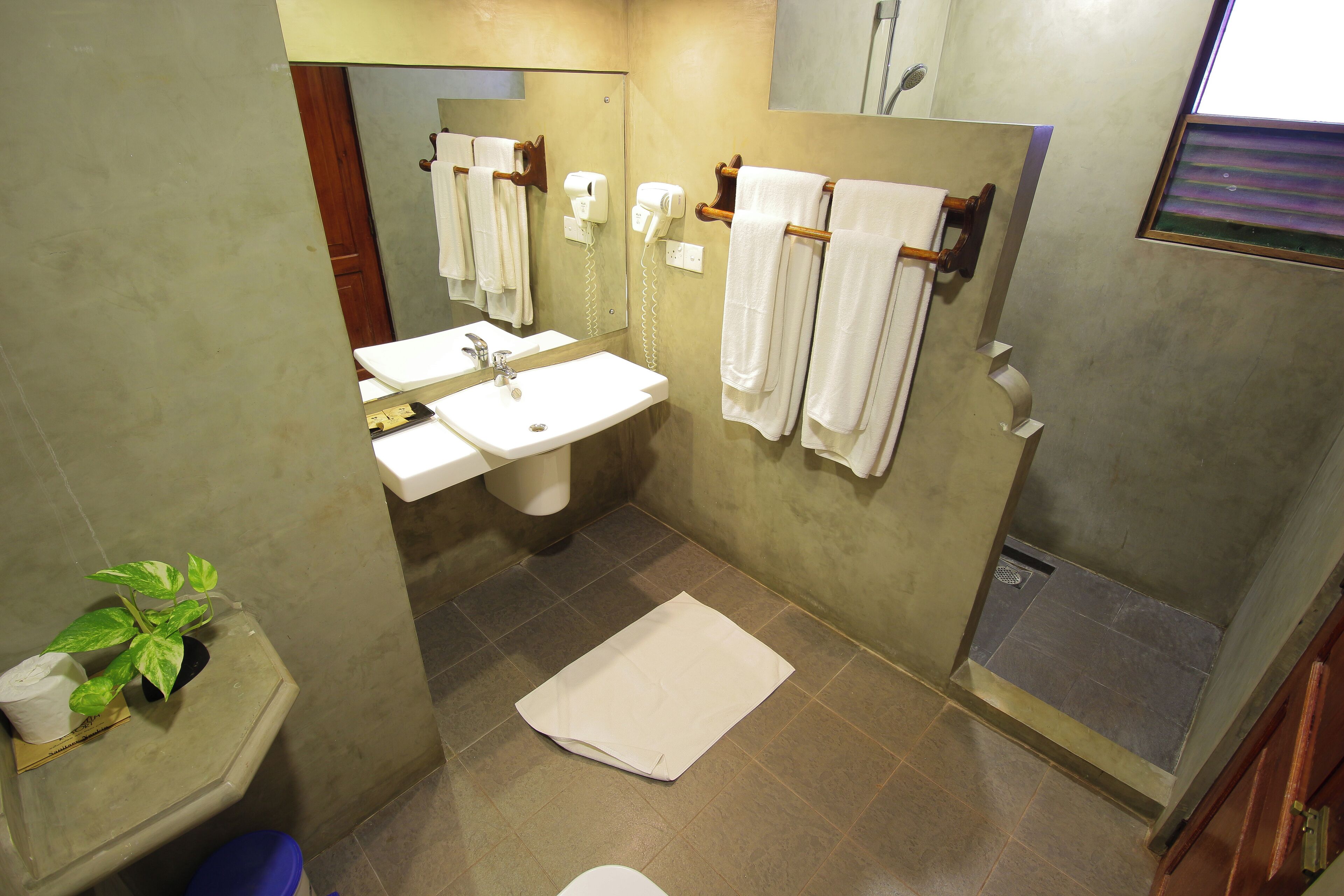 Une salle de bain équipée d’un lavabo, d’un miroir, d’un porte-serviettes et d’un espace douche.