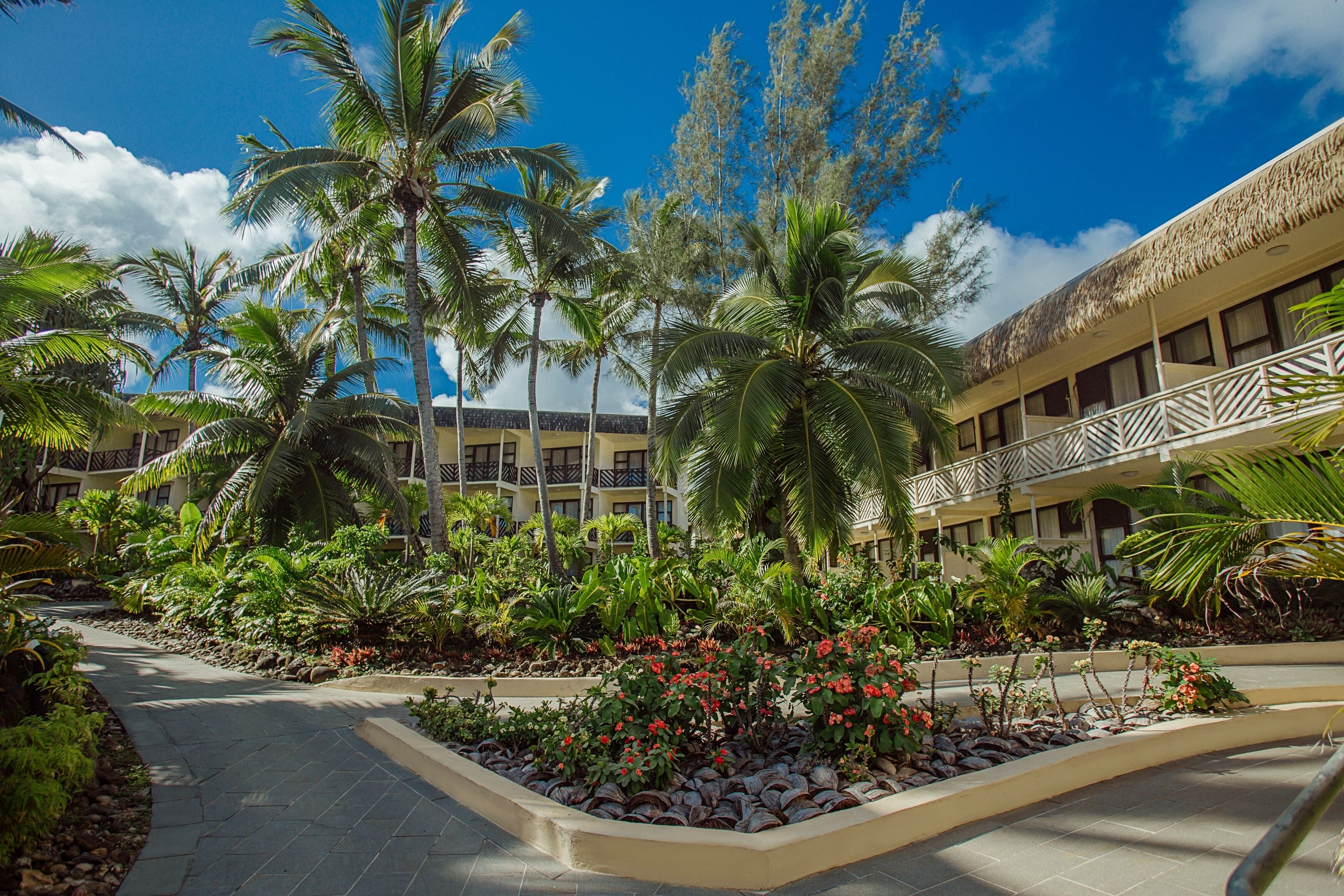 Un complexe hôtelier doté d’une piscine, de palmiers et d’un bâtiment avec des balcons.