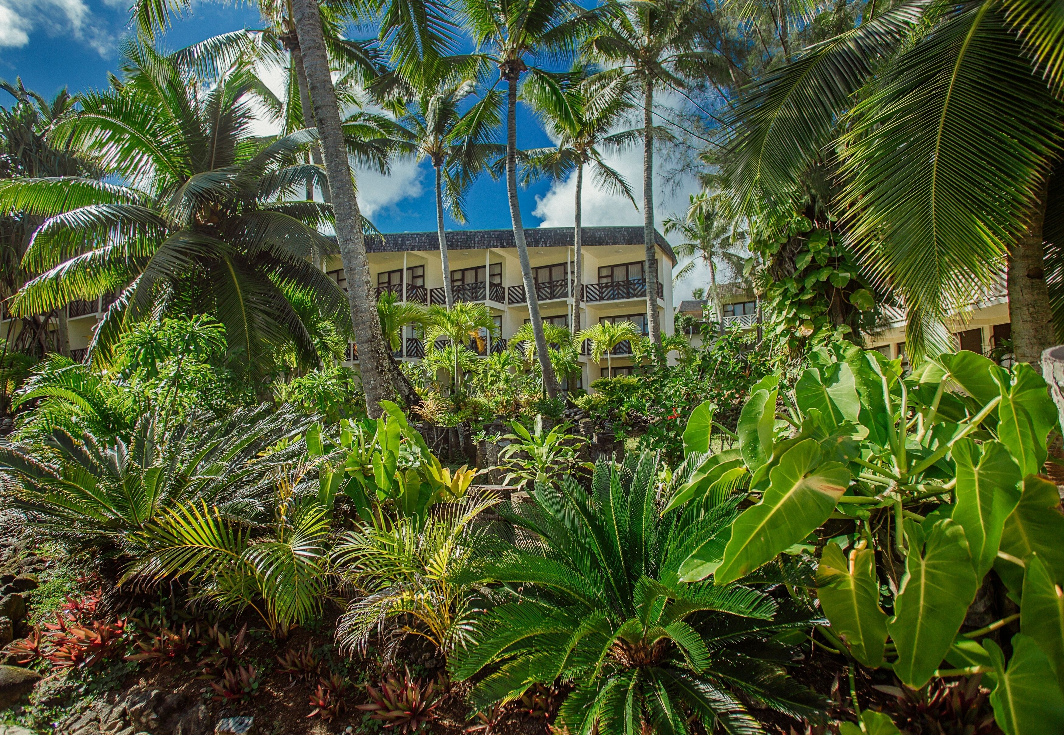 Un hotel con varios balcones, rodeado de exuberante vegetación tropical.