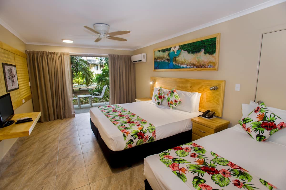 Une chambre d’hôtel avec deux lits, une télévision, un bureau et un ventilateur de plafond.