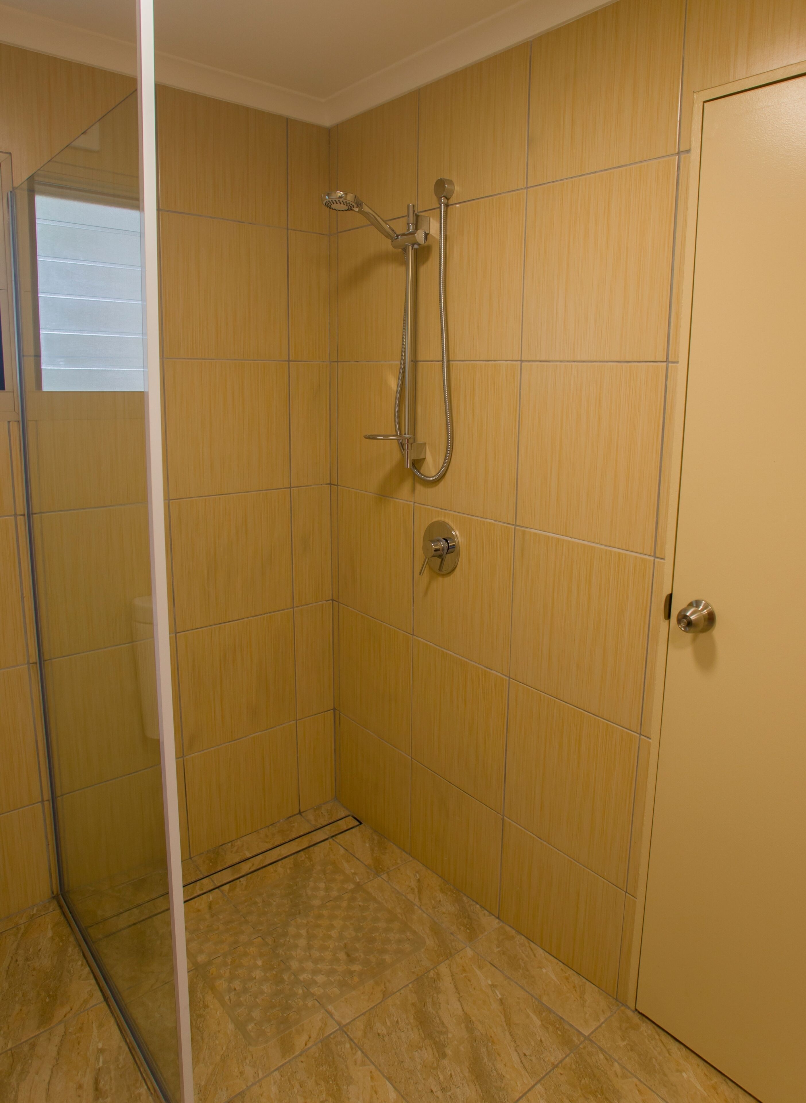 A small, enclosed shower area with a glass door, tiled walls, and a tiled floor.