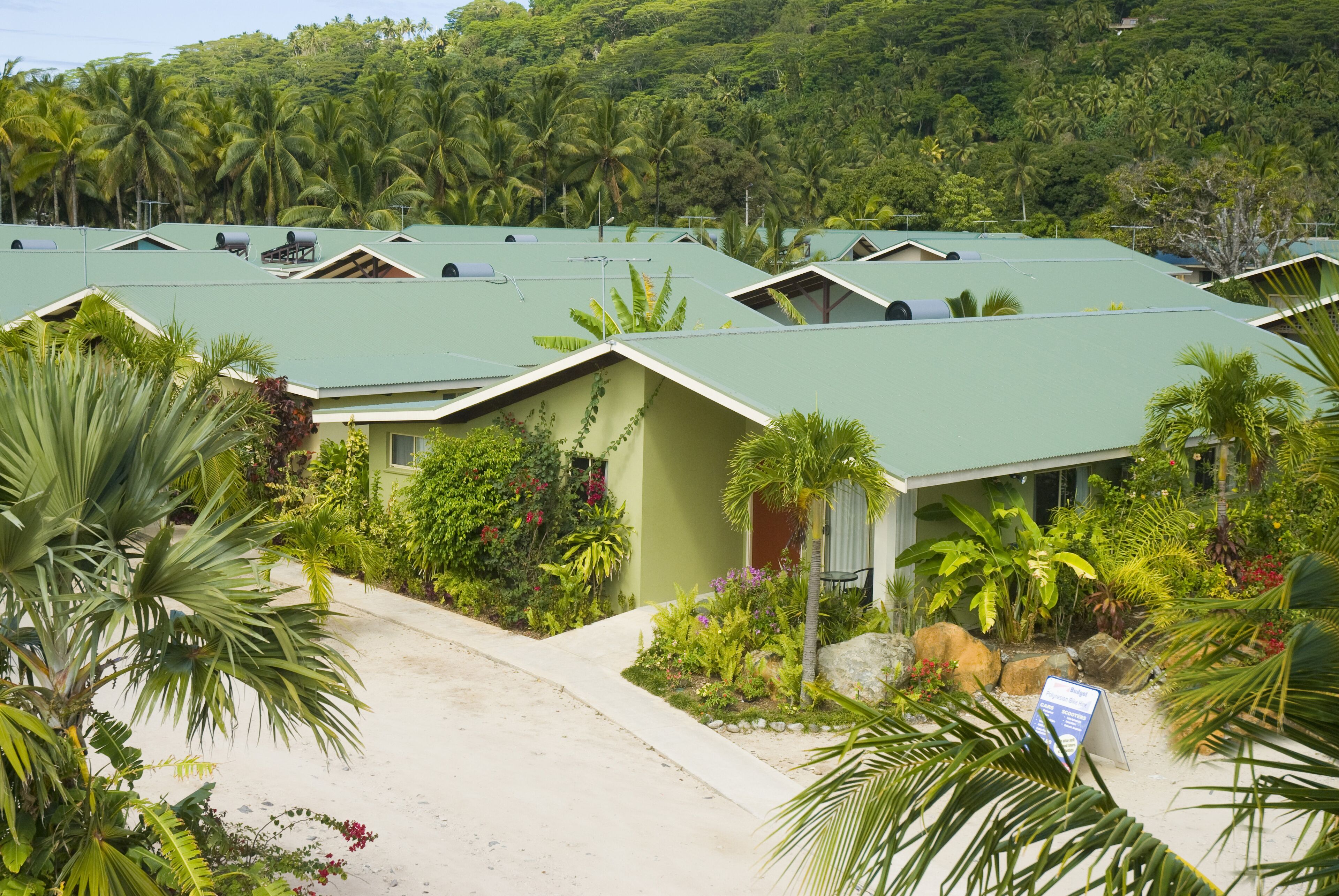 Un complexe hôtelier comprenant plusieurs bâtiments surmontés de toits végétalisés, le tout entouré d’une végétation tropicale luxuriante.