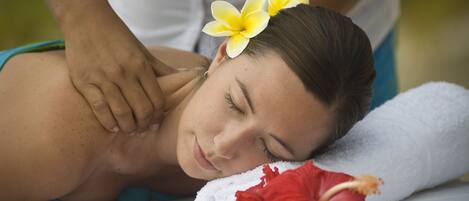 A person receiving a massage with a towel and a red flower on a massage table.
