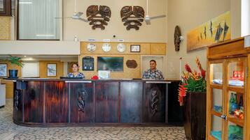 A reception desk with a clock, a television, and a plant.