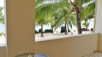 Ein Zimmer mit Blick auf einen Strand, Palmen und einen Tisch mit Blumen.