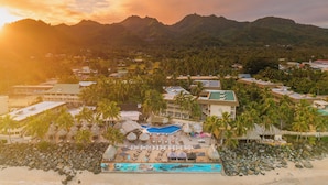 A resort with a pool, palm trees, and mountains in the background. - The Edgewater Resort & Spa (Rarotonga)