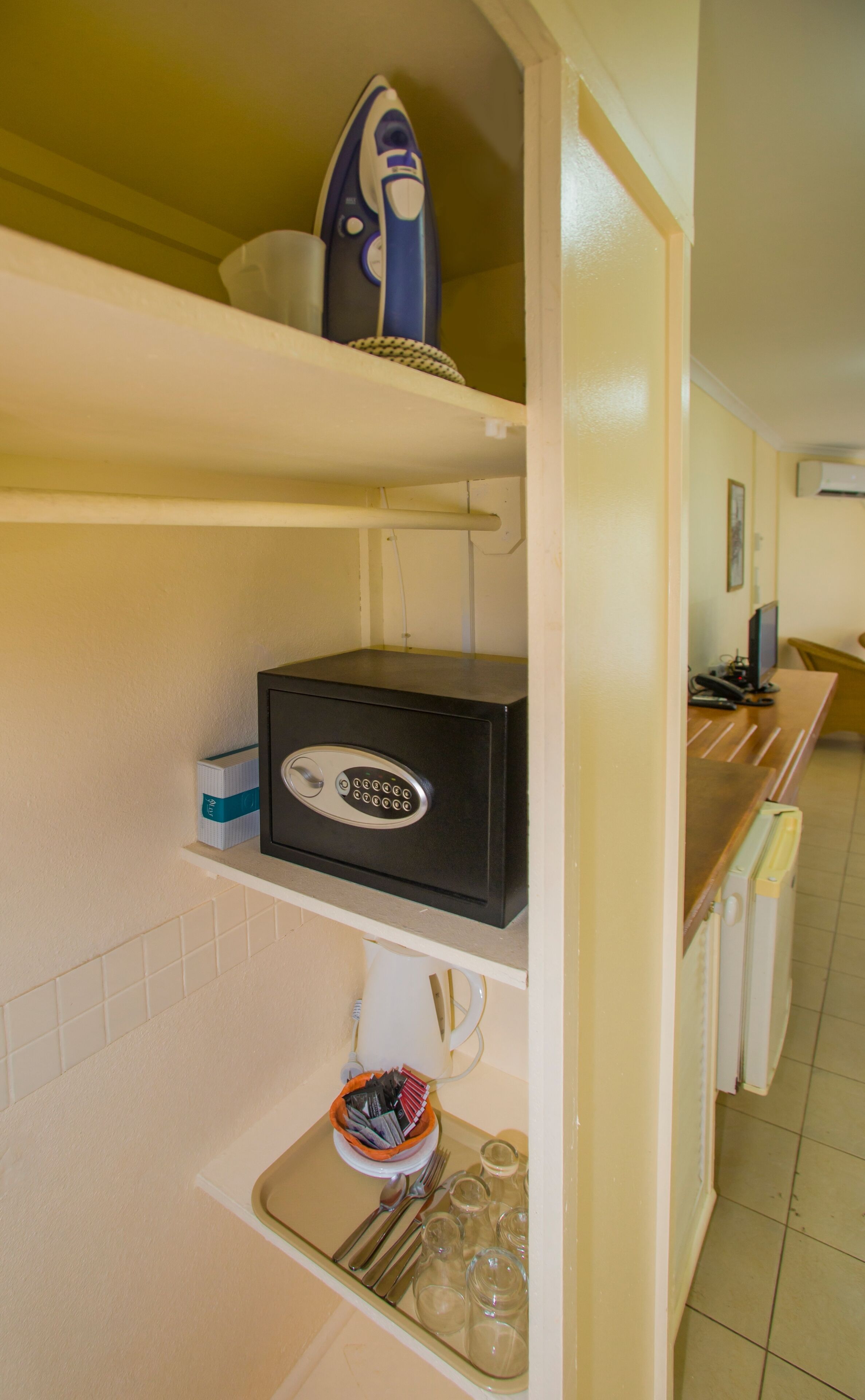 A kitchen with a black safe, an iron, and a coffee maker on the countertop.