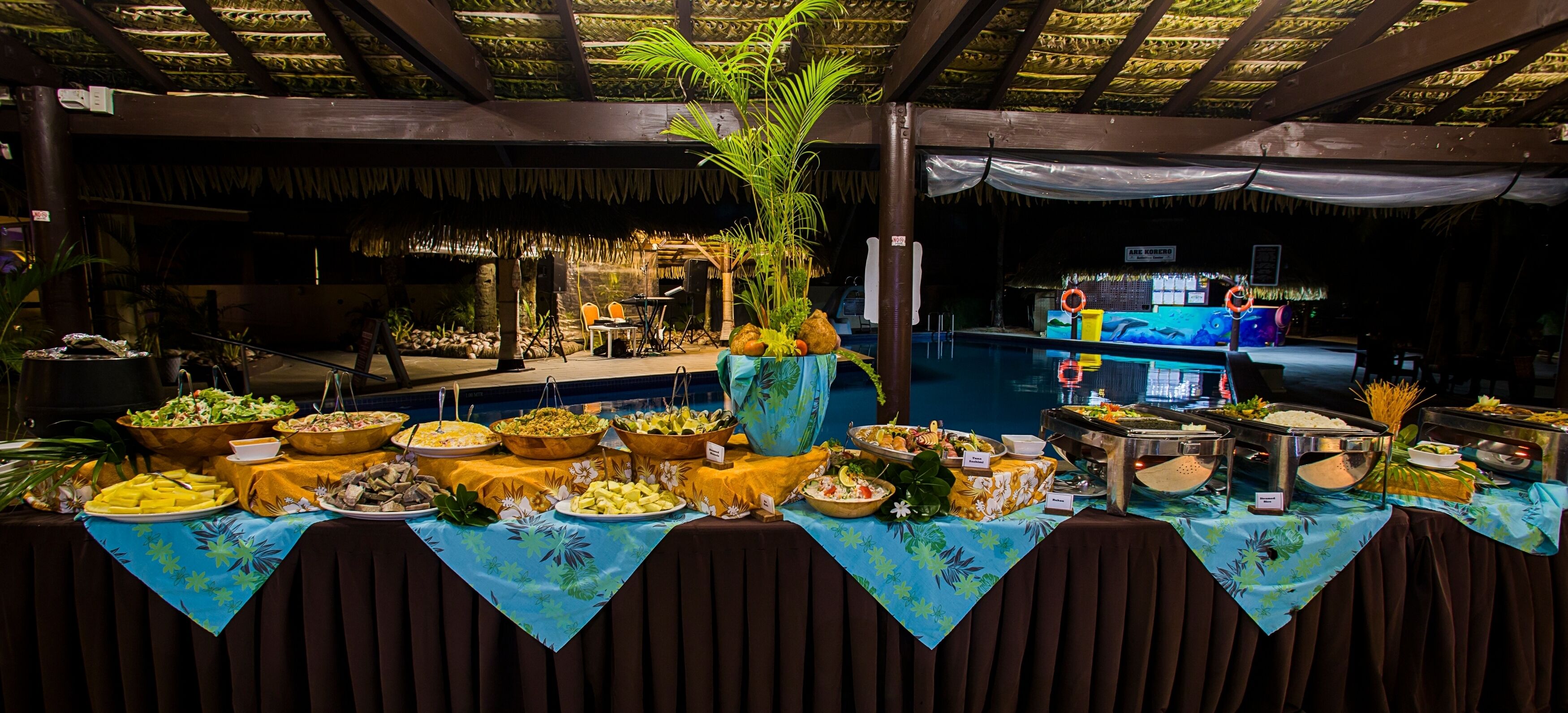 A buffet table with various food items and a pool area in the background.