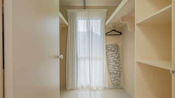A room with a white door, a white curtain, a whiteboard with writing, and a white shelf.