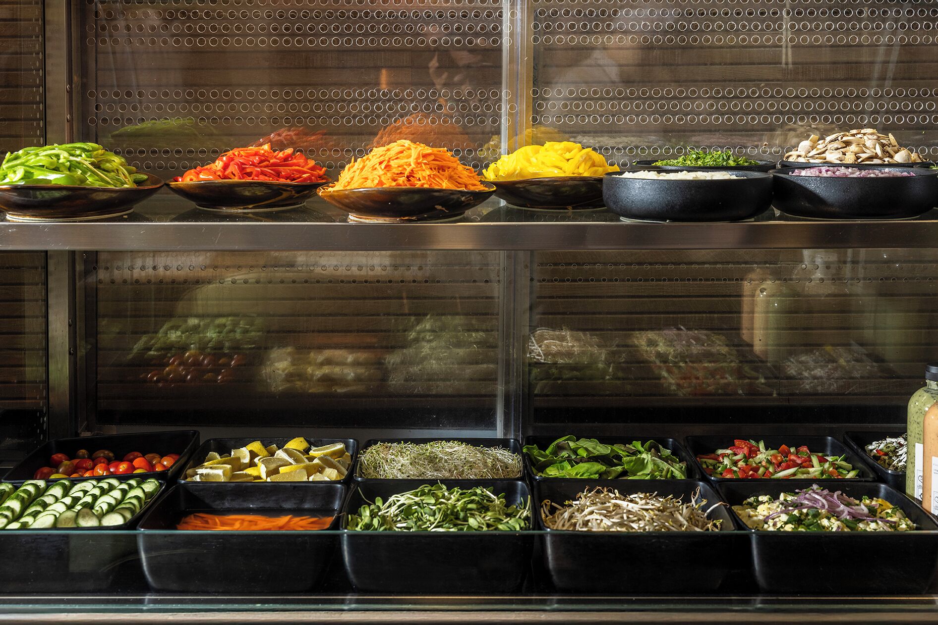 Eine Salatbar mit verschiedenen Gemüsesorten und Blattsalaten, präsentiert in Schalen.
