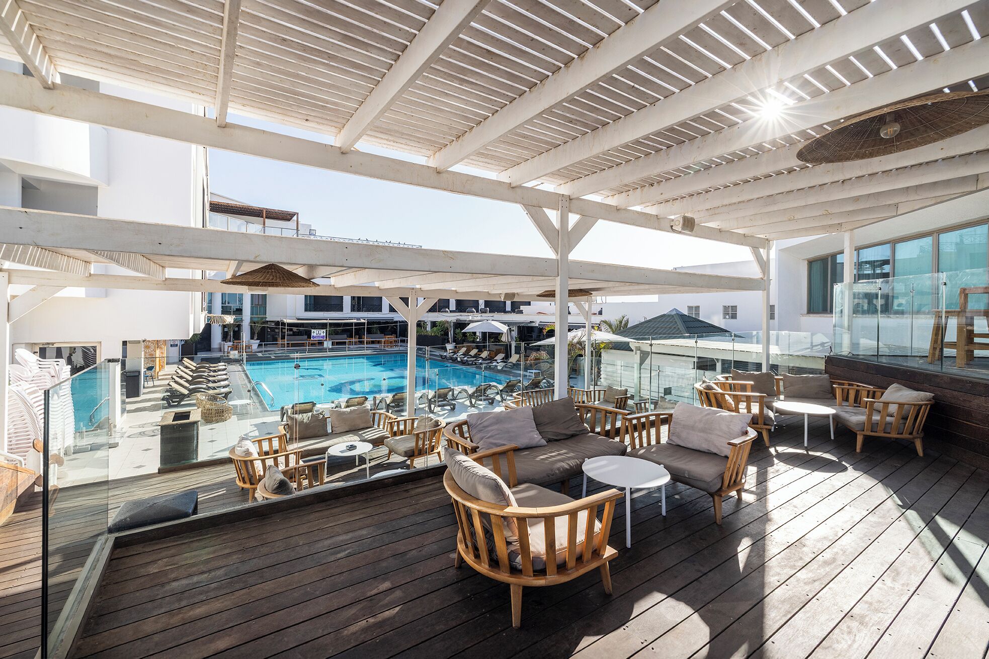 En træterrasse med udendørs møbler og et poolområde.