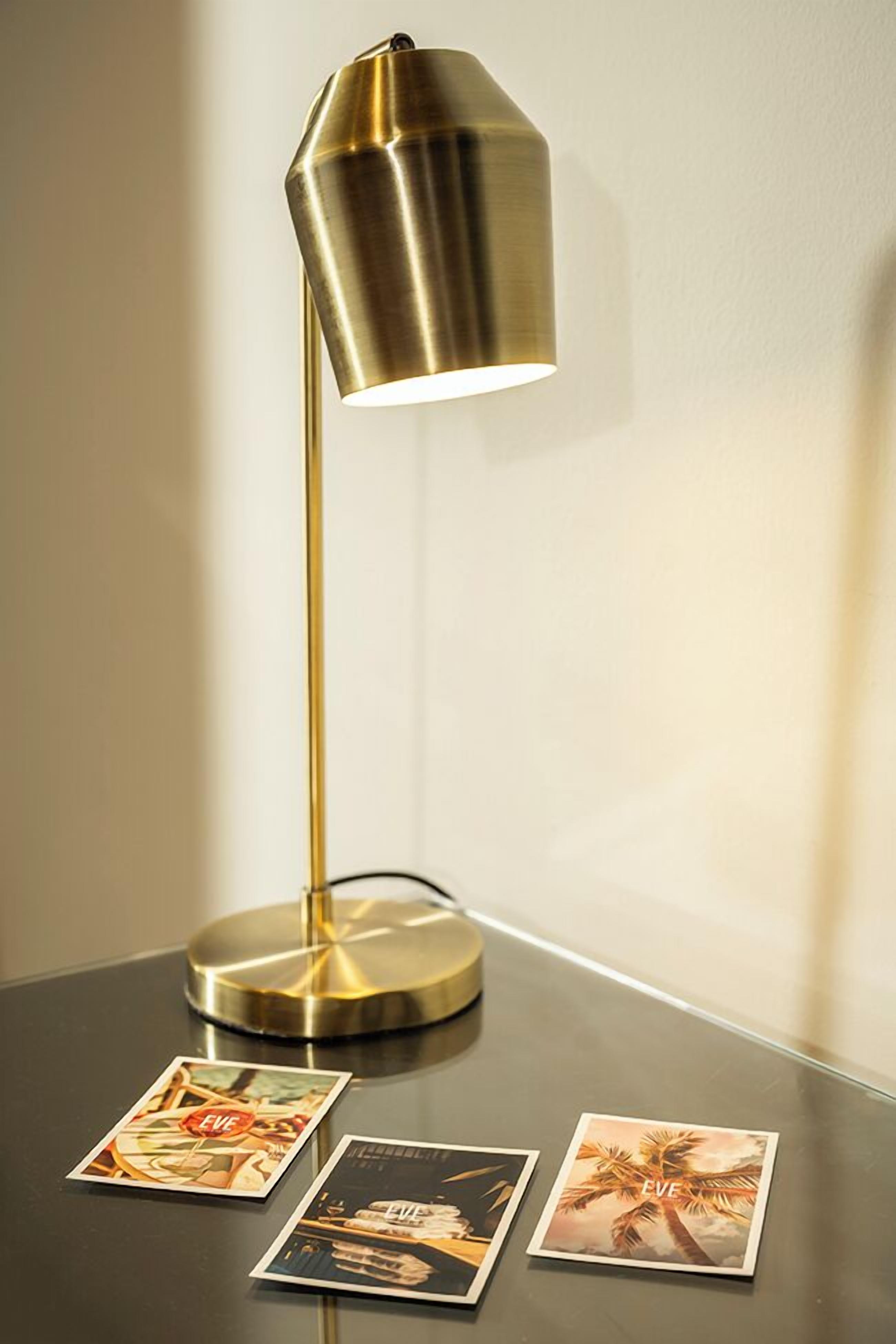 A modern floor lamp with a metallic finish on a table.