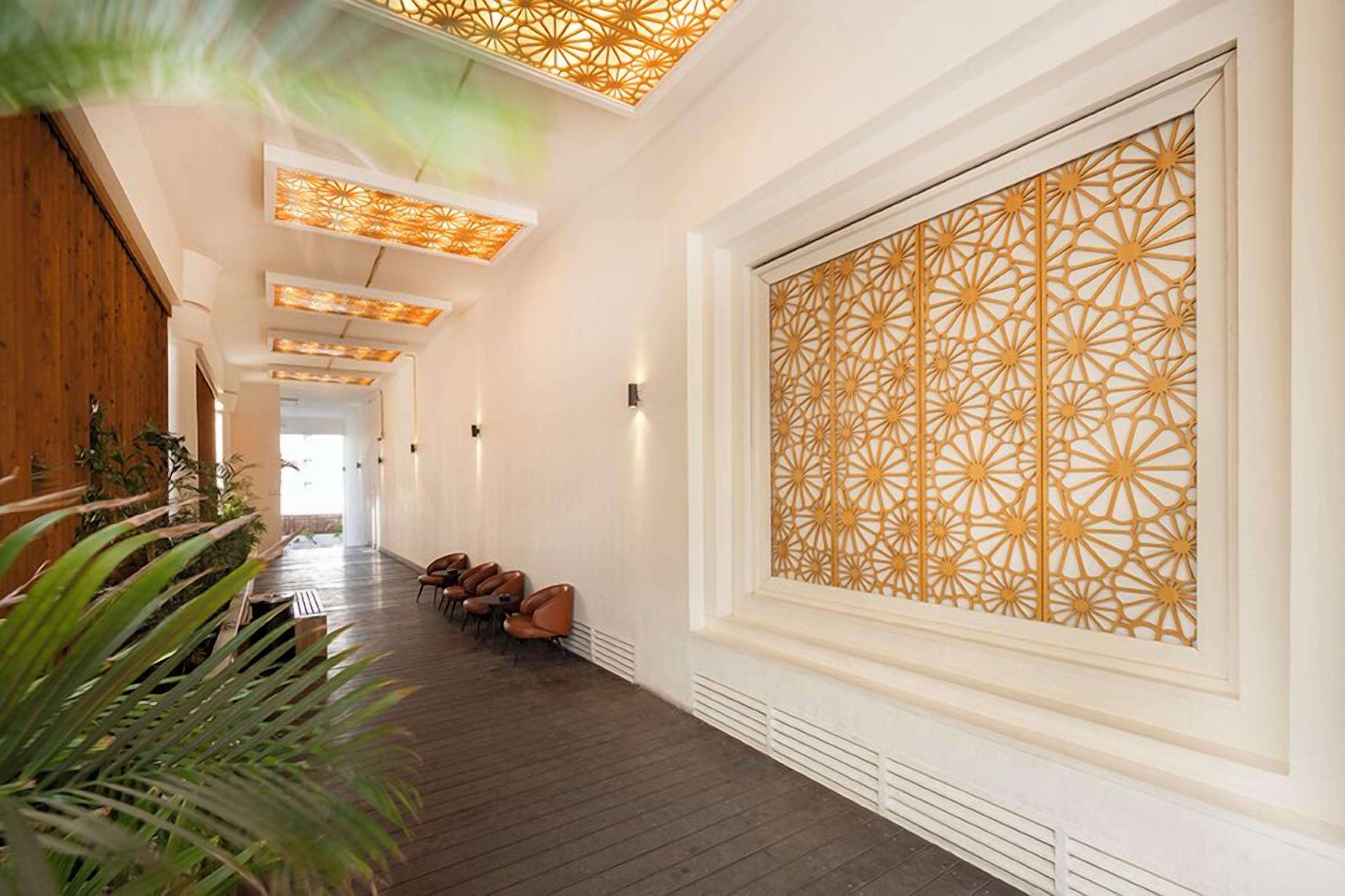 A hallway with patterned wall panels, wooden flooring, and seating areas.