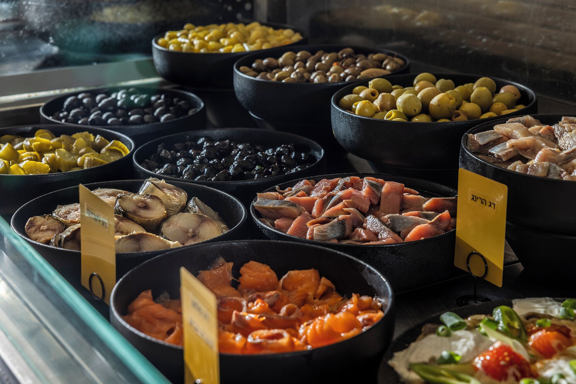 A variety of seafood dishes displayed in black bowls with price tags.