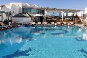 A swimming pool with lounge chairs and a covered seating area. -  EVE by Adam Hotels (Eilat)