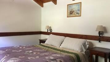 Un dormitorio con cama, dos mesitas de noche, un cuadro en la pared y techo de madera.