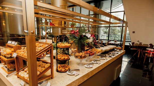 A buffet area with various baked goods and pastries displayed on wooden stands and glass bowls.