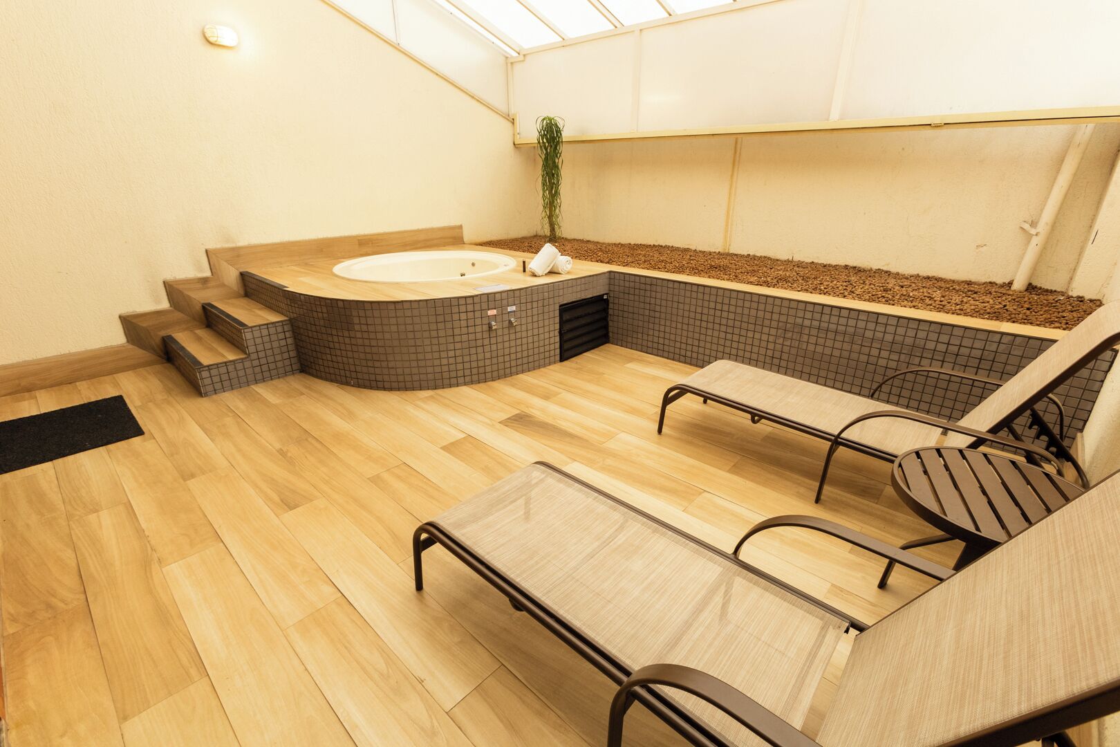 Zona de spa con jacuzzi, suelo de madera y asientos.