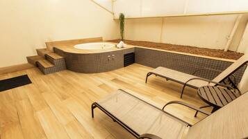 Zona de spa con jacuzzi, suelo de madera y asientos.