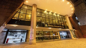 The exterior of the Royal Golden Hotel with a large glass facade, prominent signage, and a well-lit entrance area.
