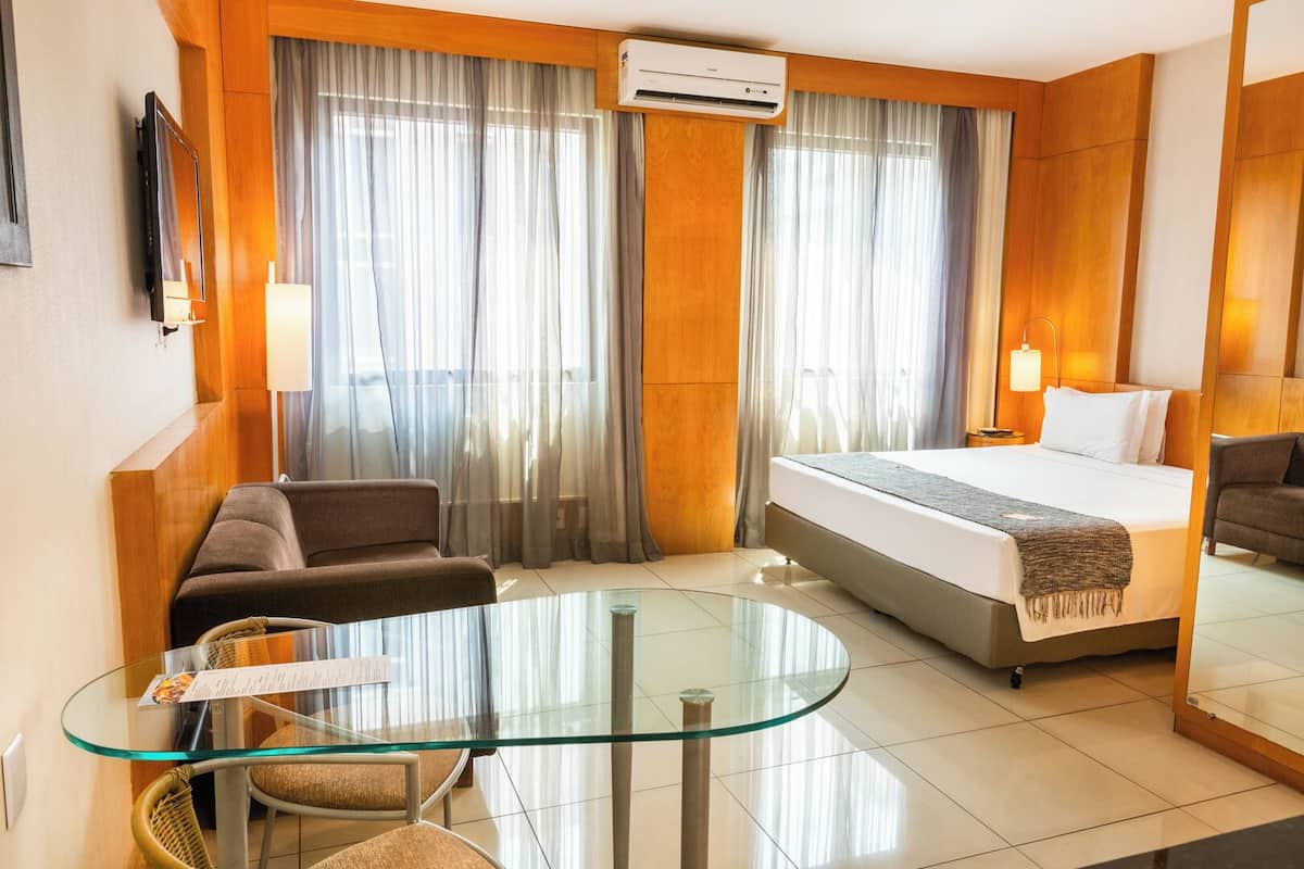 Une chambre d’hôtel avec un lit, un canapé, une table en verre et un téléviseur.