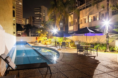 Una piscina al aire libre, sillones reclinables de piscina
