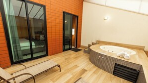 A modern bathroom with a large bathtub, wooden flooring, and a glass shower enclosure.