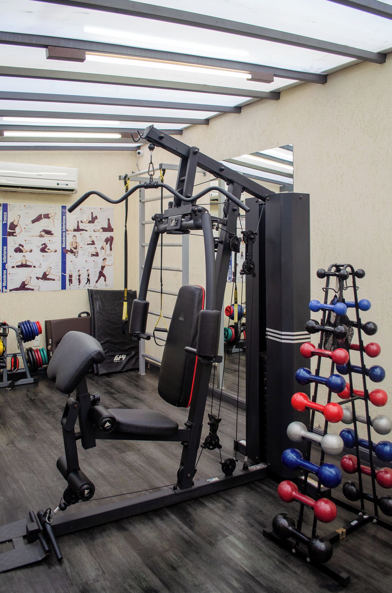 A gym with exercise equipment, a bench, and a rack of dumbbells.