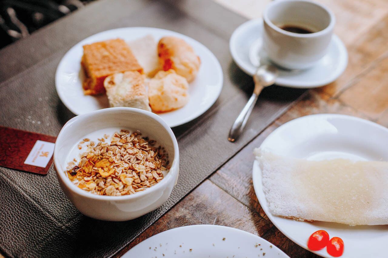 Une table avec des assiettes de nourriture, un bol de granola et une tasse de café.