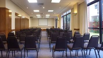 A conference room with rows of chairs, a projector screen, and large windows.