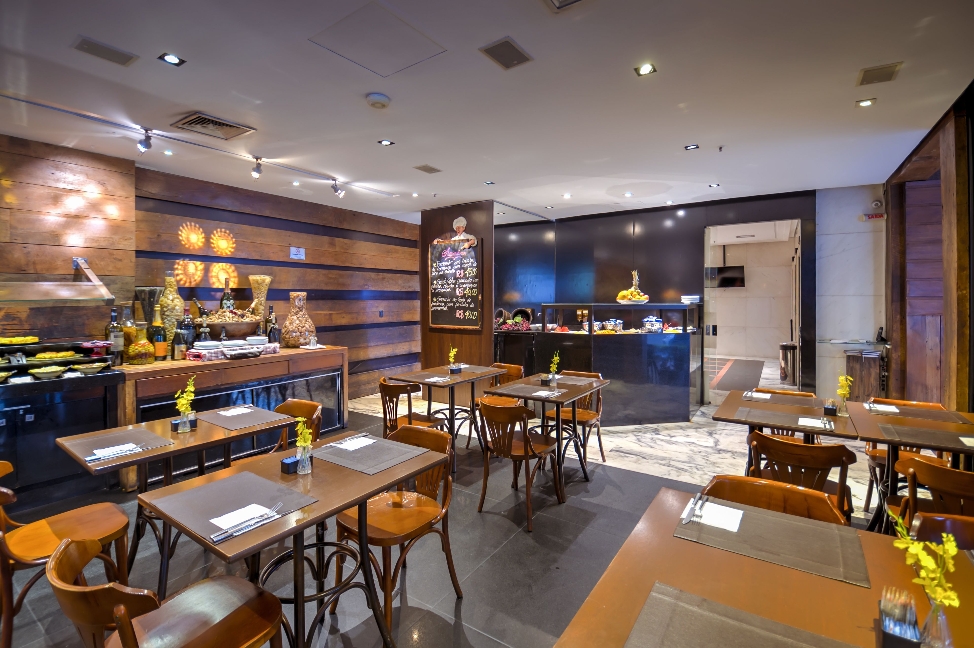 Un restaurante moderno con decoración de madera, una zona de bar y una cocina visible al fondo.