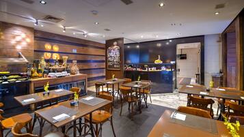 Un restaurante moderno con decoración de madera, una zona de bar y una cocina visible al fondo.