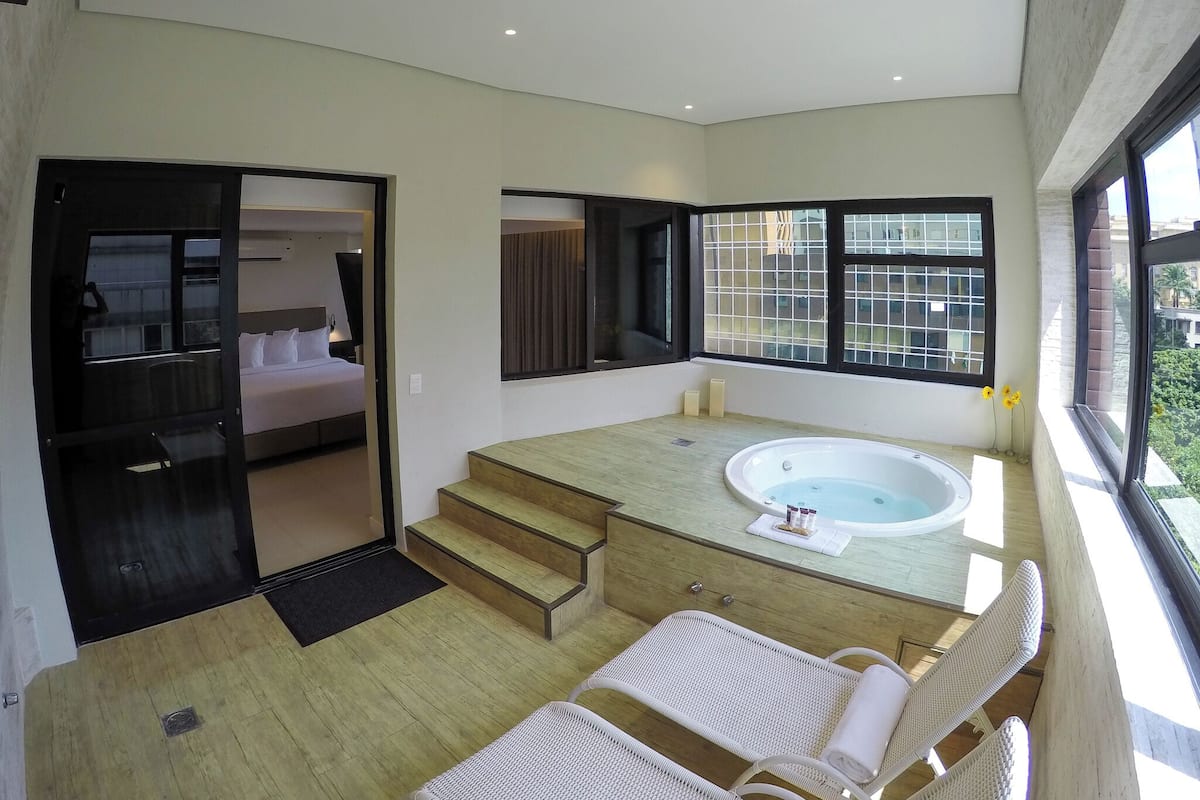 Ein modernes Badezimmer mit einer Badewanne, einem Spiegel und einem Fenster.