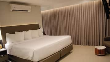 A modern hotel room with a large bed, an air conditioning unit, a bedside table, a lamp, and a drum.