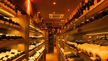A wine cellar with shelves of wine bottles and a central walkway.