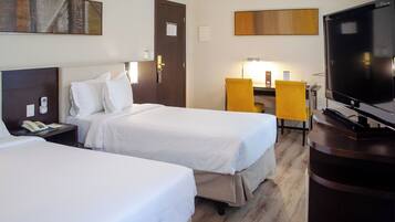 A hotel room with two beds, a desk with a chair, a TV, and a telephone.