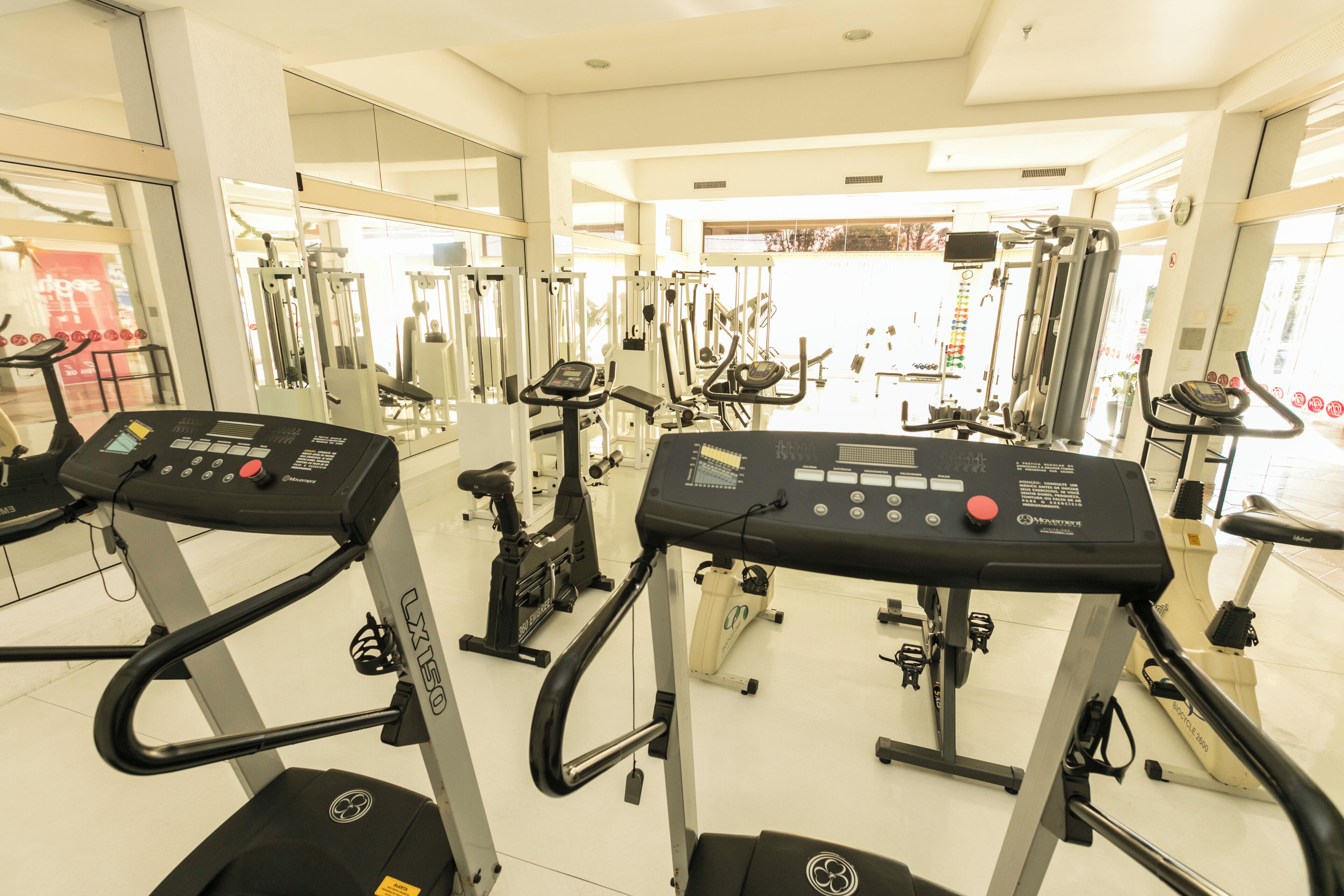 Una sala de gimnàstica amb cintes de córrer, el·líptiques i aparells de musculació.