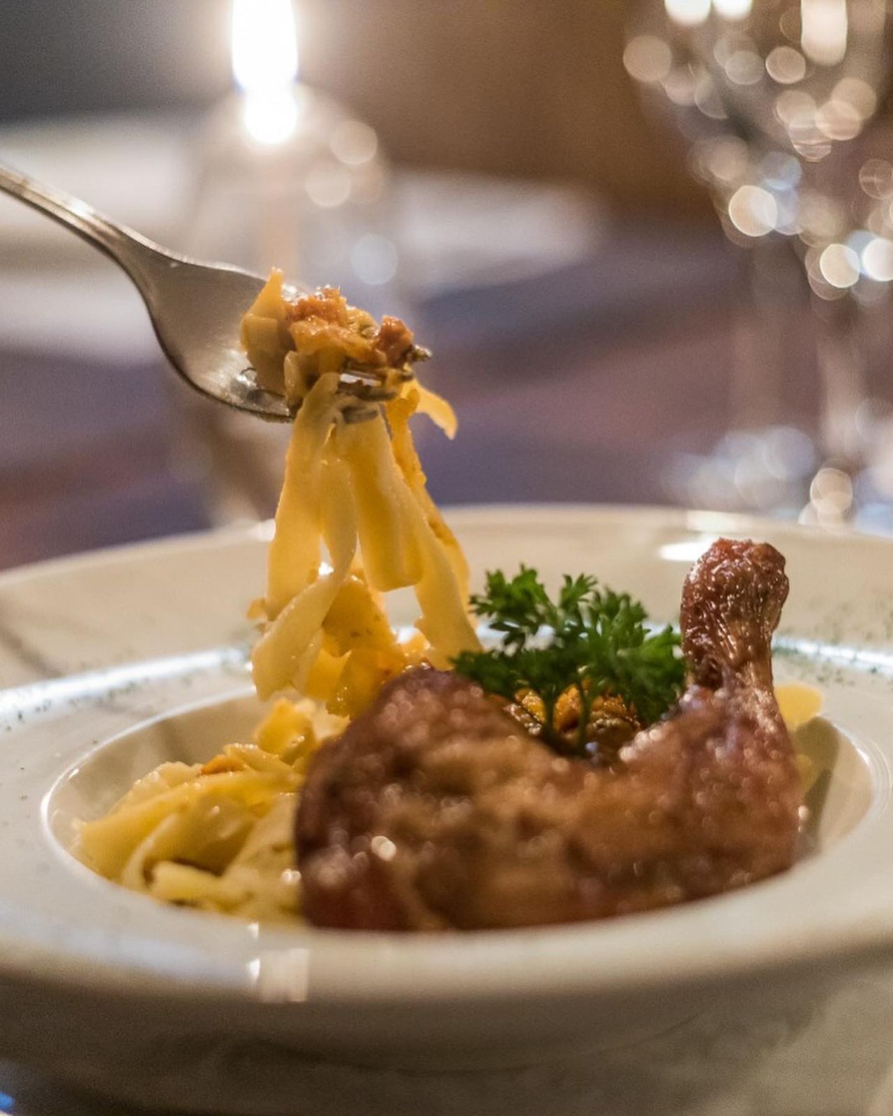 A plate with pasta and a piece of meat, possibly chicken, garnished with parsley.